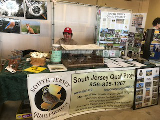 A man sitting behind a table with the SJQP banner